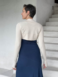 caraucci-woman-wearing-cream-sleeve-shrug-layered-over-navy-dress-with-thumbhole-detail #color_cream