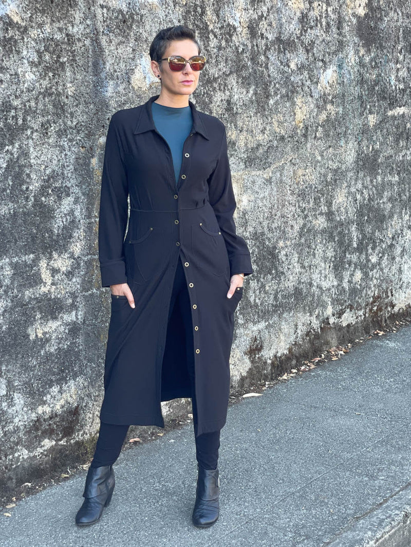 caraucci bamboo spandex black coat dress with 6 pockets and brass buttons up the front, can be worn as a jacket or dress #color_black