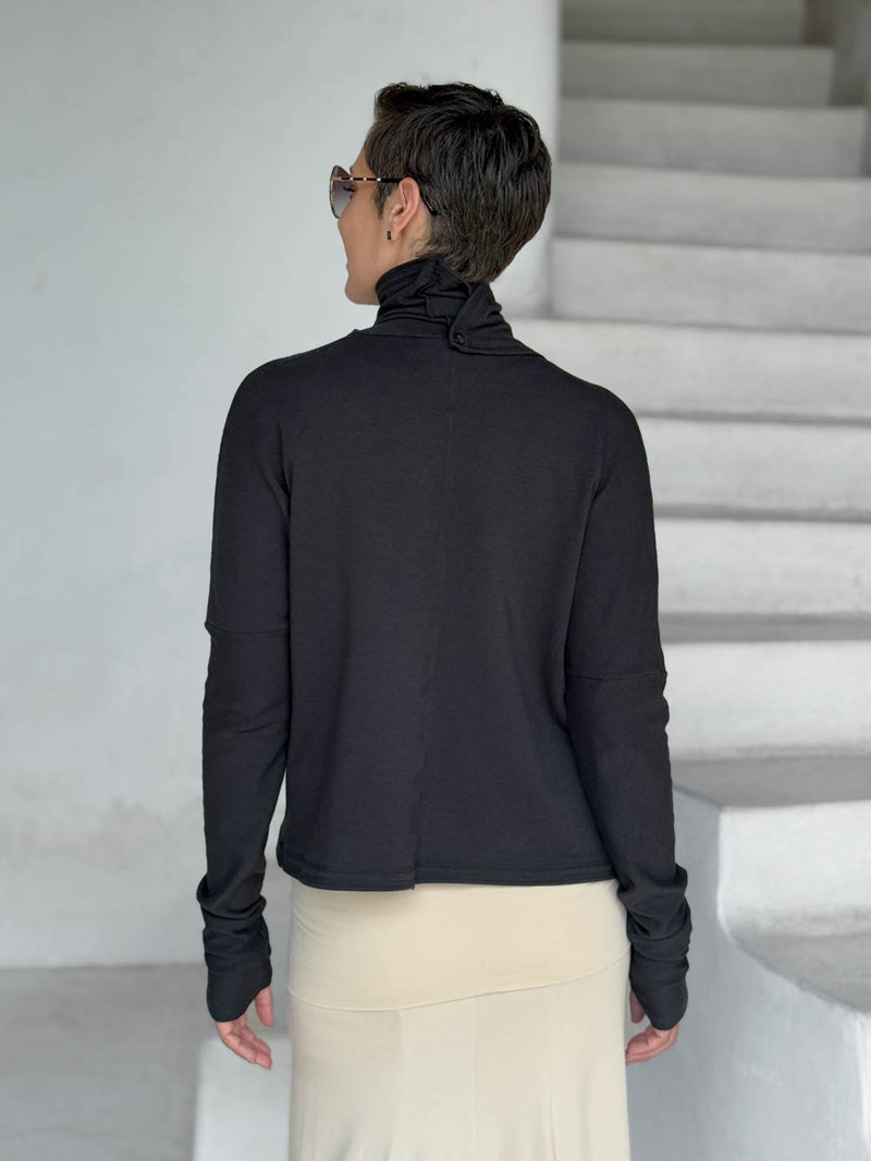 caraucci black bamboo fleece jacket, shown buttoned into a high cowl neck, from the back, with thumbholes and pockets #color_black