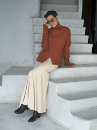 caraucci orange bamboo fleece jacket, shown buttoned into a high cowl neck with thumbholes and pockets worn with a cream full skirt #color_copper
