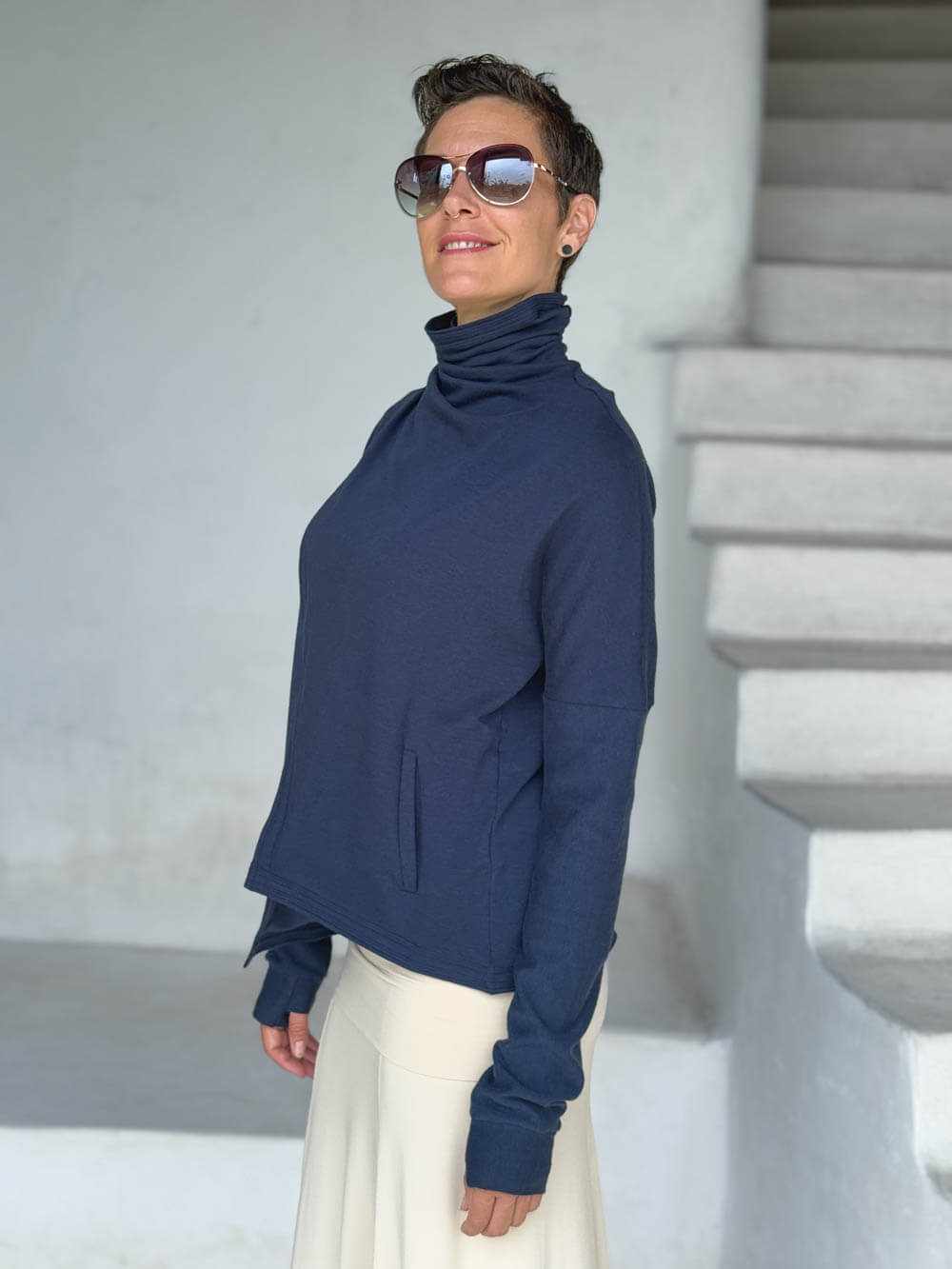 caraucci navy blue bamboo fleece jacket, shown buttoned into a high cowl neck with thumbholes and pockets #color_navy