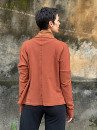 caraucci orange bamboo fleece jacket, shown buttoned into a high cowl neck with thumbholes and pockets #color_copper