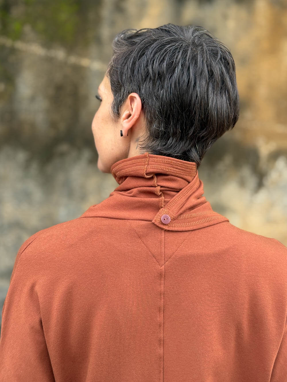 caraucci orange bamboo fleece jacket, shown buttoned into a high cowl neck with thumbholes and pockets #color_copper