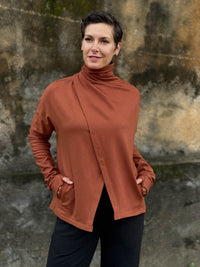 caraucci orange bamboo fleece jacket, shown buttoned into a high cowl neck with thumbholes and pockets #color_copper