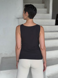 caraucci-woman-wearing-black-boat-neck-tank-top-in-rayon-jersey-layered-over-cream-pants #color_black