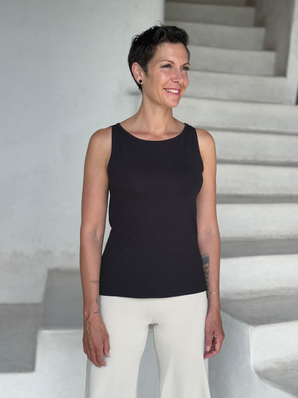 caraucci-woman-wearing-black-boat-neck-tank-top-in-rayon-jersey-layered-over-cream-pants #color_black