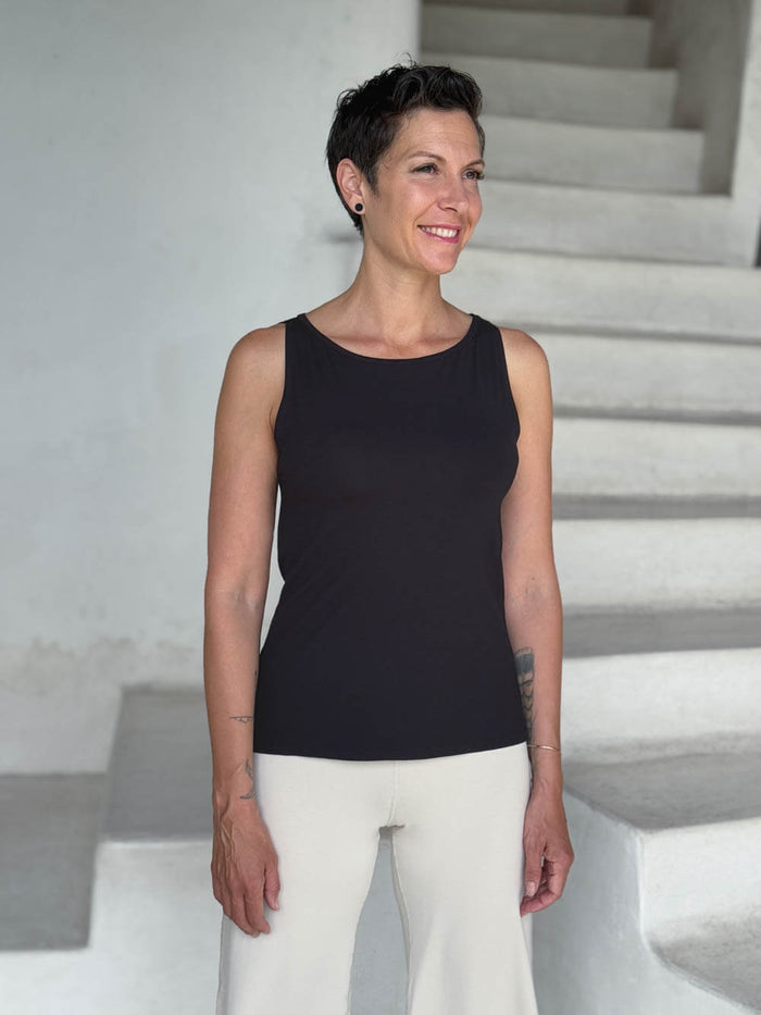 caraucci-woman-wearing-black-boat-neck-tank-top-in-rayon-jersey-layered-over-cream-pants #color_black