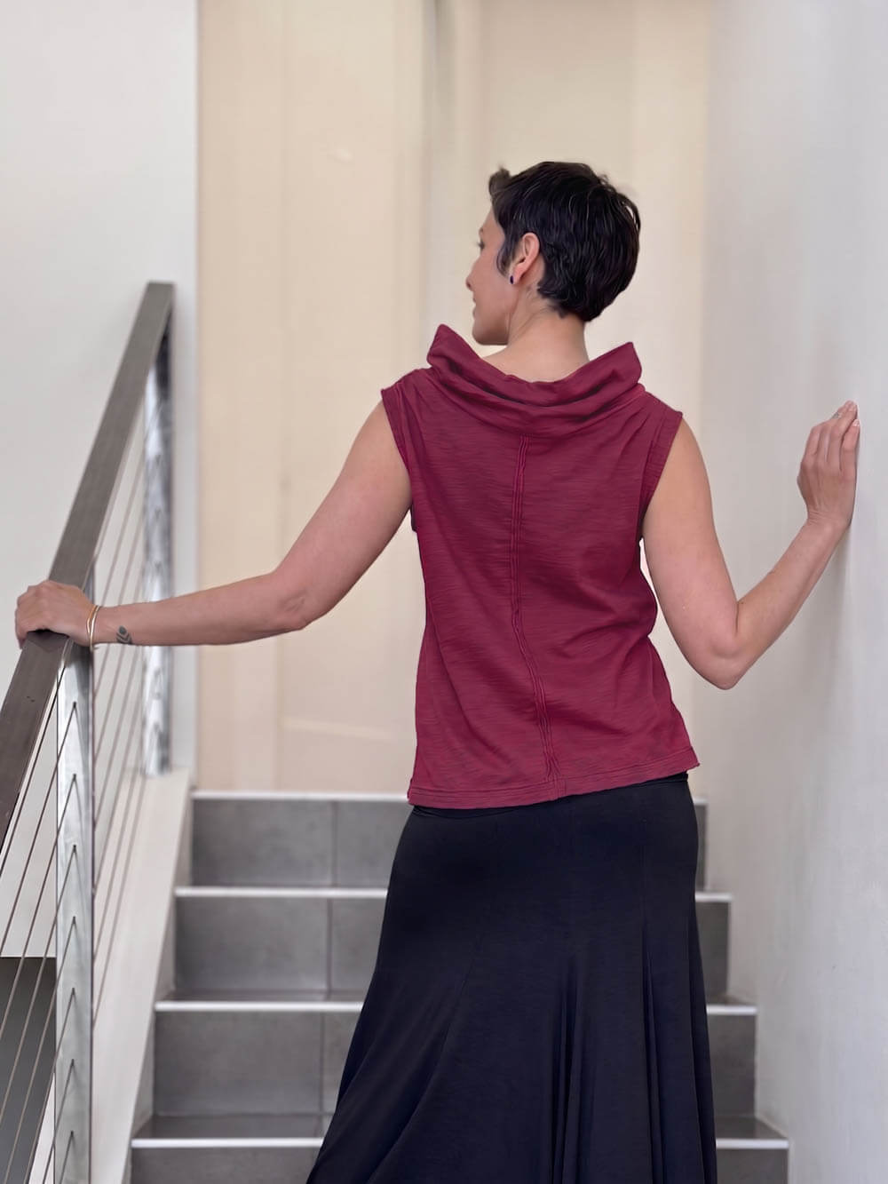 Back view of CARAUCCI Cotton Cowl Neck Tank in crimson maroon with draped neckline, center seam detail and black skirt. #color_crimson