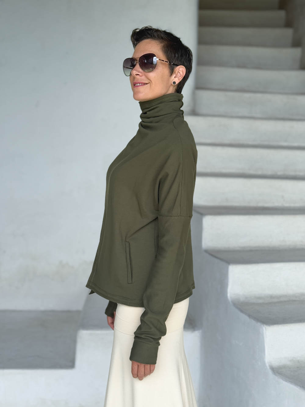 caraucci forest green bamboo fleece jacket, shown buttoned into a high cowl neck with thumbholes and pockets #color_forest