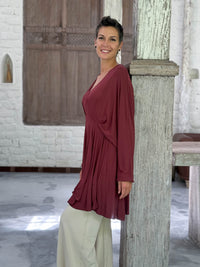 caraucci peplum tunic in maroon lightweight rayon jersey with v neckline and asymmetrical hem #color_wine